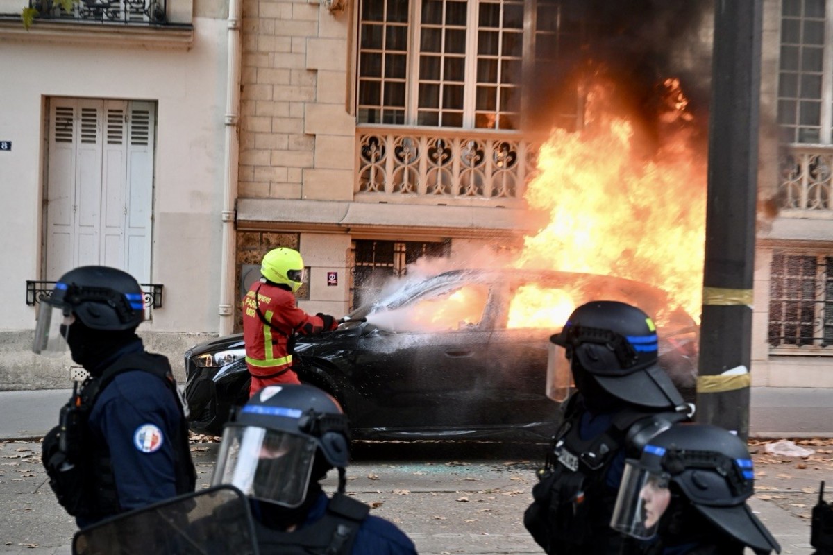 Một lính cứu hỏa nỗ lực dập tắt đám cháy tại chiếc ô tô trên đường phố Paris (Pháp). Ảnh: Bộ Nội vụ Pháp