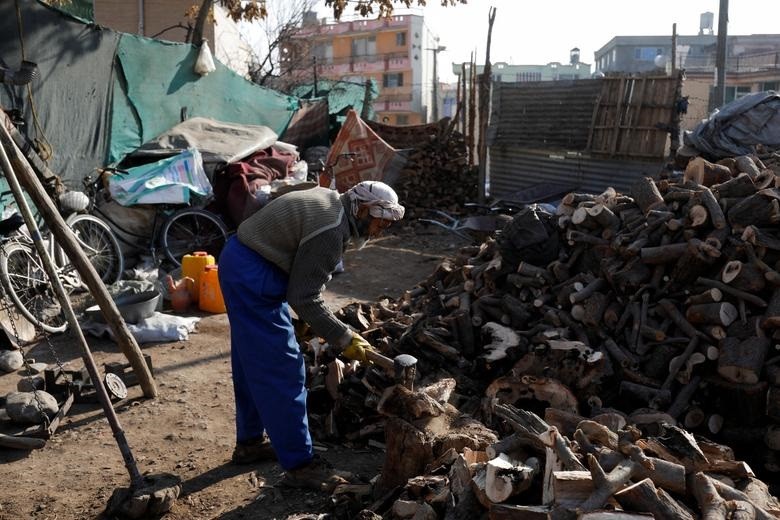 Một người đ&agrave;n &ocirc;ng l&agrave;m việc trong cửa h&agrave;ng củi. Nhiều người d&acirc;n Afghanistan kh&ocirc;ng đủ tiền để mua củi, than để sưởi ấm. Ảnh: Reuters