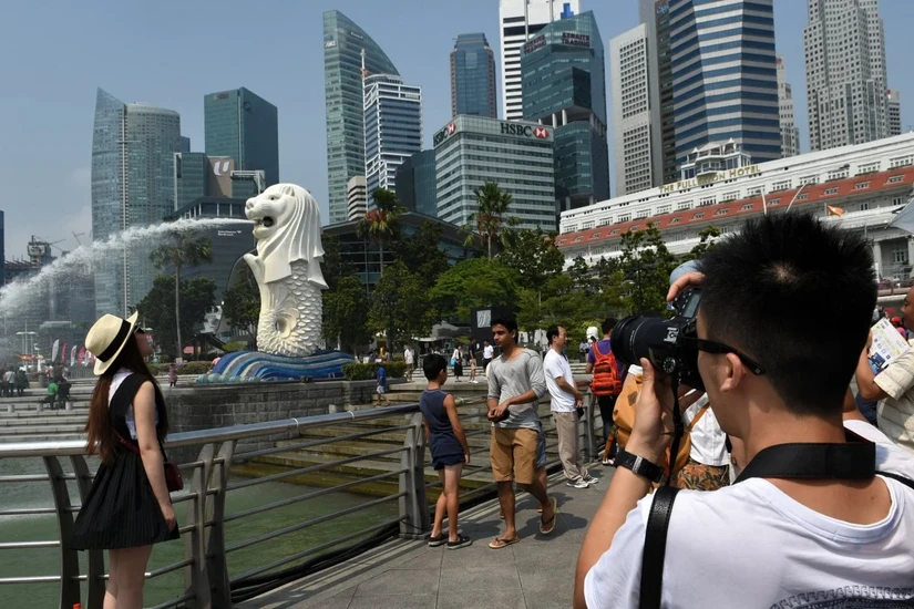 Du kh&aacute;ch Trung Quốc chụp ảnh trước tượng sư tử biển Merlion ở Singapore. Ảnh: AFP