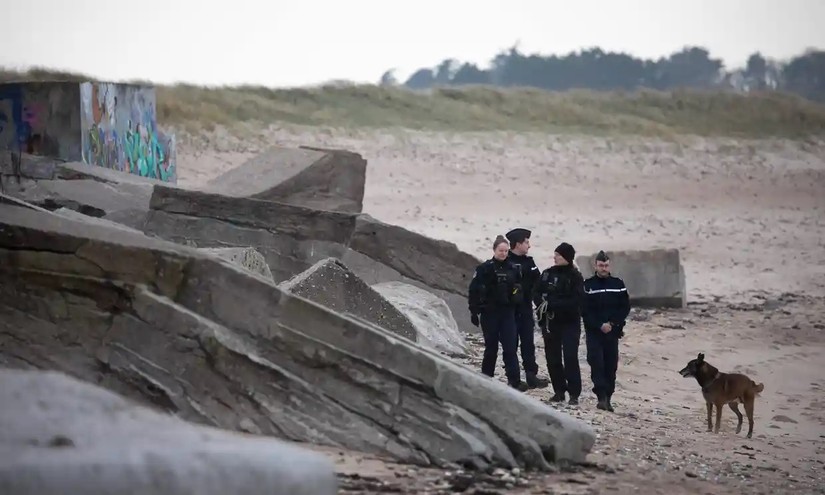 Cảnh s&aacute;t Ph&aacute;p v&agrave; ch&oacute; nghiệp vụ tuần tra tr&ecirc;n b&atilde;i biển Neville sur Mer, thuộc v&ugrave;ng Normandy. Ảnh: AFP