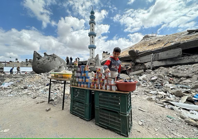 Một cậu b&eacute; đứng cạnh c&aacute;c đồ hộp trong ng&agrave;y cầu nguyện thứ S&aacute;u trong th&aacute;ng ăn chay Ramadan ở Rafah, ph&iacute;a nam Gaza, ng&agrave;y 22/3. Ảnh: Reuters