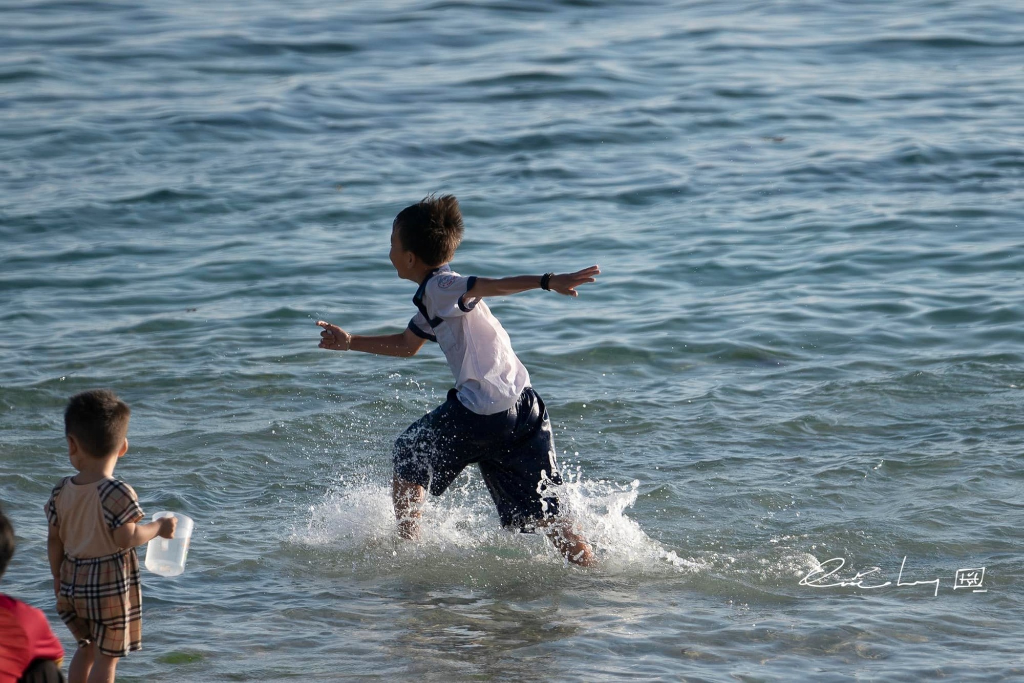 Những đứa trẻ trên đảo đi học về, để nguyên đồng phục học sinh, chúng lao xuống chơi đùa với sóng. Ảnh: Quốc Huy Những đứa trẻ trên đảo đi học về, để nguyên đồng phục học sinh, chúng lao xuống chơi đùa với sóng. Ảnh: Quốc Huy