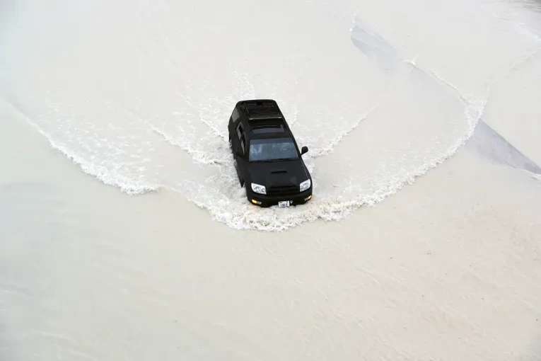 Xe &ocirc; t&ocirc; l&aacute;i qua d&ograve;ng nước lũ tại Dubai, UAE. Ảnh: Al Jazeera