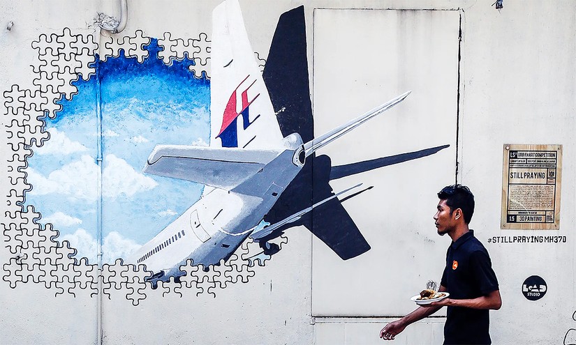 Người đ&agrave;n &ocirc;ng đi ngang bức tường vẽ tranh tưởng niệm chuyến bay MH370 tại Kuala Lumpur, Malaysia, th&aacute;ng 2/2016. Ảnh: AP