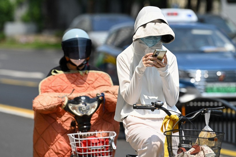 Người d&acirc;n Trung Quốc mặc quần &aacute;o chống nắng dưới thời tiết nắng n&oacute;ng ở Thượng Hải, ng&agrave;y 29/5. Ảnh: AFP