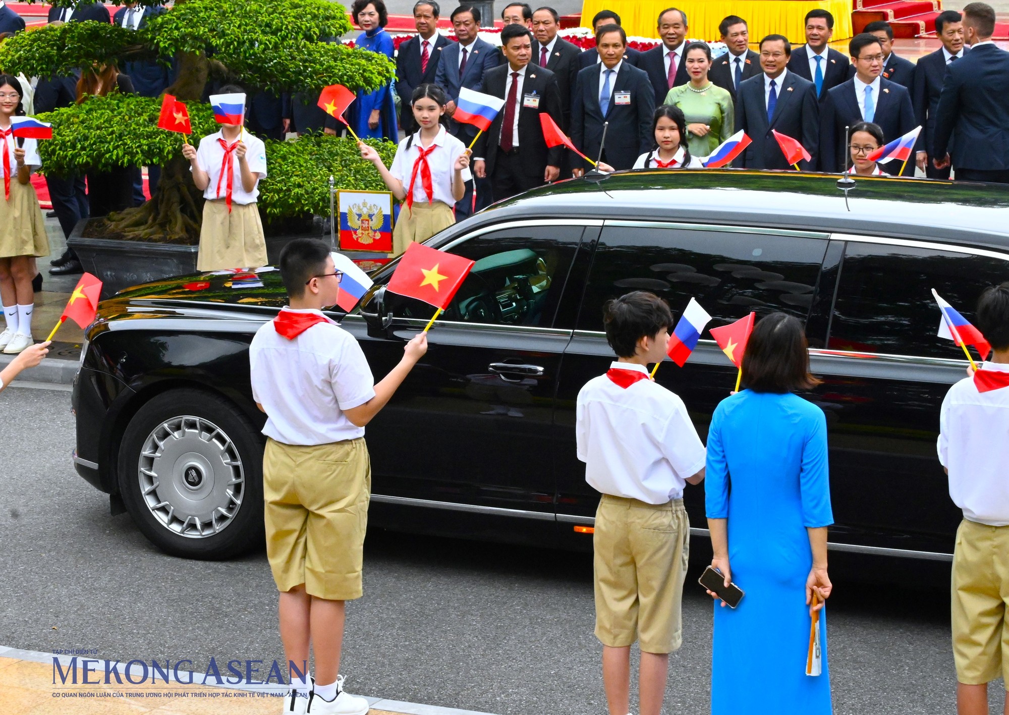 Chuy&ecirc;n xa Aurus Senat Limousine do Nga sản xuất chở Tổng thống Putin c&ugrave;ng đo&agrave;n hộ tống tiến v&agrave;o Phủ Chủ tịch giữa hai h&agrave;ng thiếu nhi vẫy cờ ch&agrave;o mừng. Ảnh: Đỗ Thảo - Mekong ASEAN