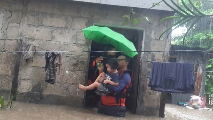 Lực lượng cứu hộ bế đứa b&eacute; vượt qua khu vực nước lũ. Ảnh: AFP