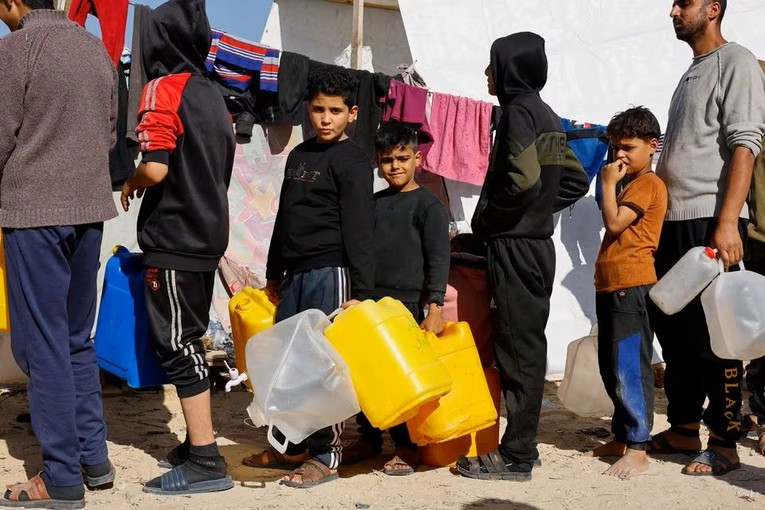 Trẻ em Palestine xếp h&agrave;ng chờ lấy nước tại một trại tị nạn gần bi&ecirc;n giới Rafah, ng&agrave;y 11/12. Ảnh: Reuters